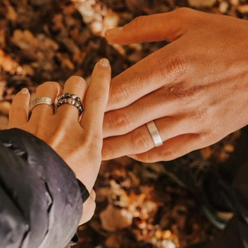 Couple qui se donne la main, laissant voir les bagues qu’ils ont forgées lors d’un atelier duo “fabriquez vos alliances en argent” chez Sealvie