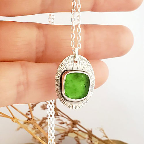Médaille en argent ovale sertie d'un éclat de verre dépoli vert, motifs de traits fins martelés, montée sur chaîne en argent, atelier Sealvie